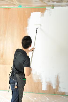 person using roller to paint wall